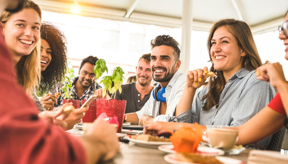 Junge Menschen sitzen beim Essen zusammen im Alpha Kurs und lachen